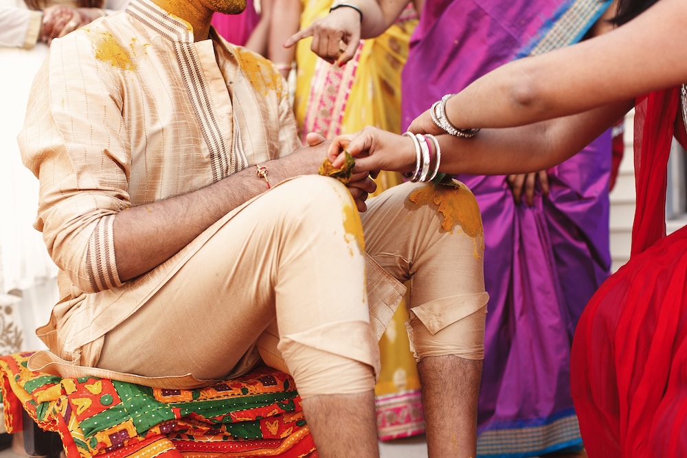 Prints of red palms put over the shirt of Indian groom sitting on the floor